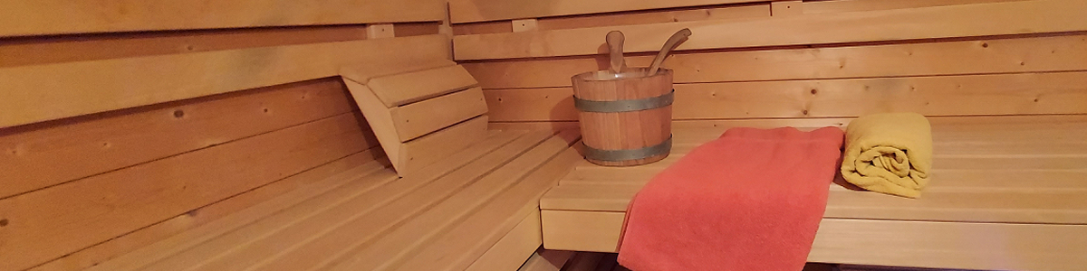 Unser Bio Saunaofen Bild zeigt eine Liegefläche in einer Sauna mit einem Saunakübel und einem roten und gelben Handtuch.